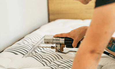 Professional cleaner using an extraction tool on a mattress